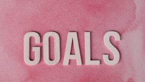 Motivational word 'GOALS' on a pink watercolor background for inspiration.